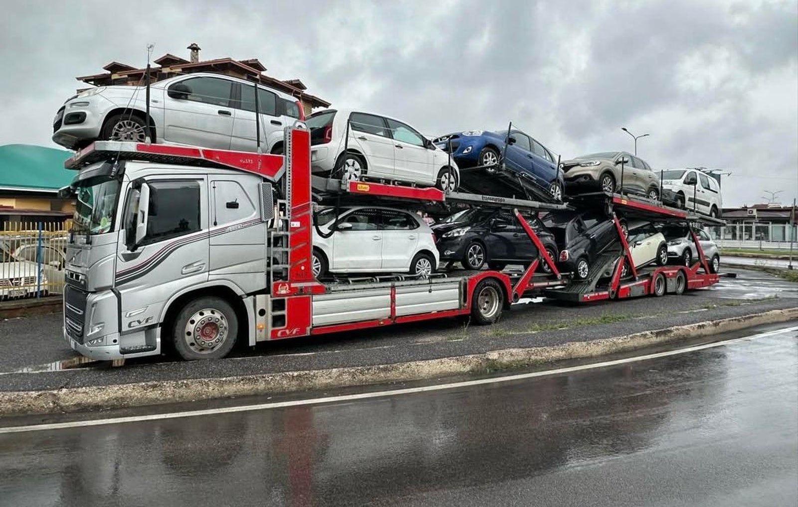 Bisarca Volvo di CVF con il carico completo di auto nuove sui due piani, ferma sulla strada bagnata