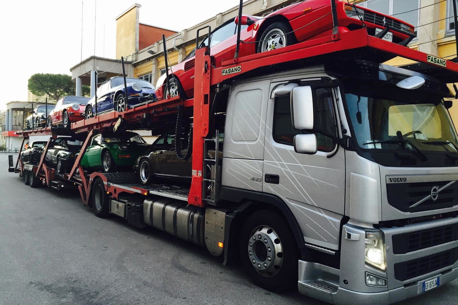 Bisarca Volvo di CVF carica di auto d'epoca: una Ferrari Testarossa rossa sul piano alto e diverse Porsche 911