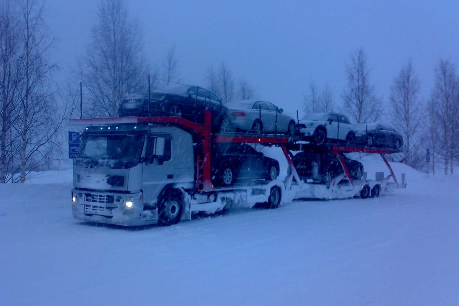 Bisarca di CVF carica di auto in viaggio su una strada innevata, con la neve che cade