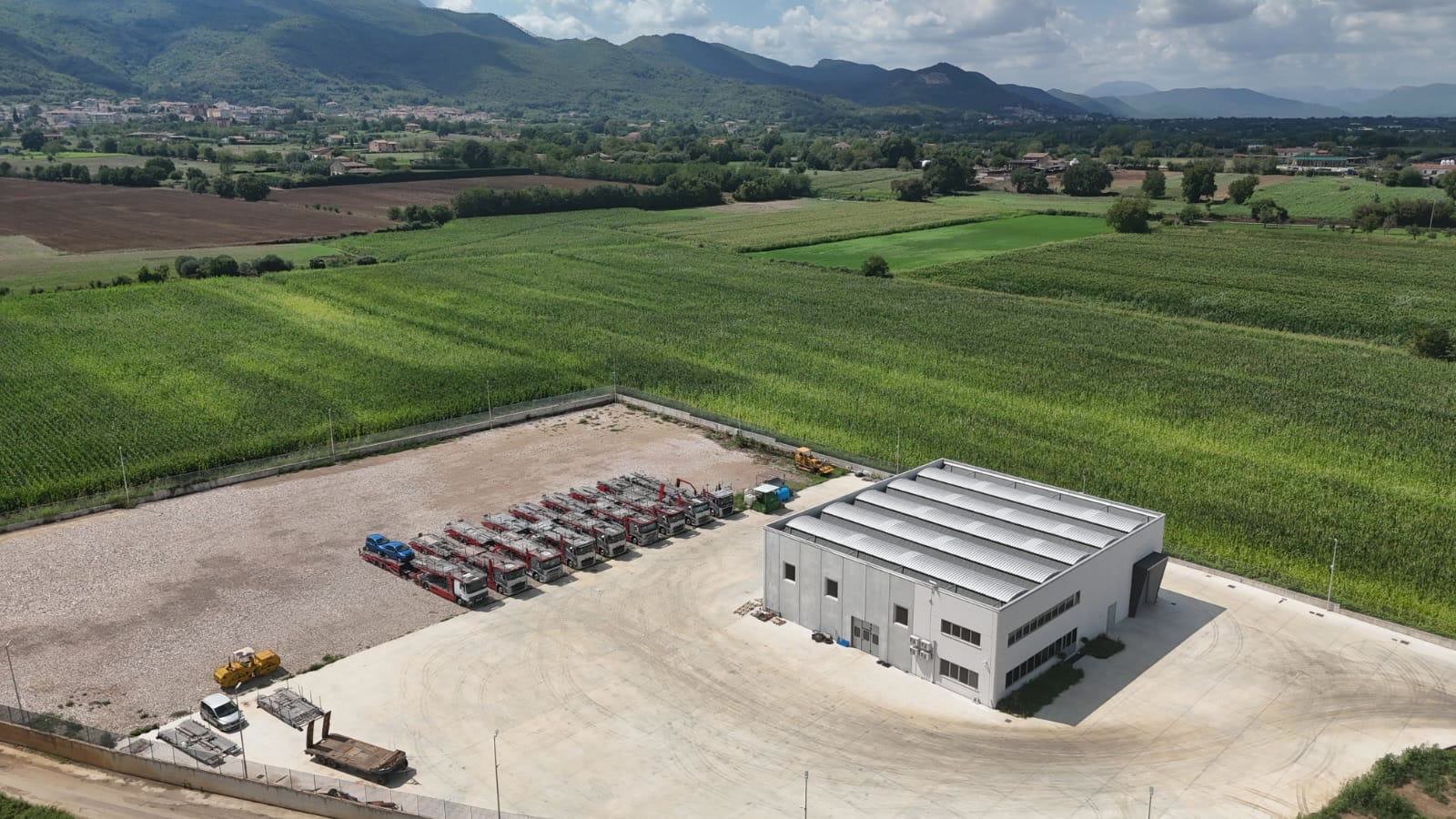 La sede e la flotta viste dal drone, di giorno, con i campi e le montagne dietro